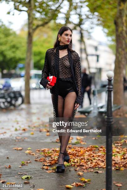 Guest wears gold earrings, black sheer mesh black polka dotted scarf, black sheer mesh black polka dotted long sleeve shirt, black mini shorts, shiny...