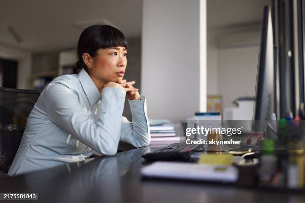 worried japanese female programmer working on pc in the office. - female programmer stock pictures, royalty-free photos & images