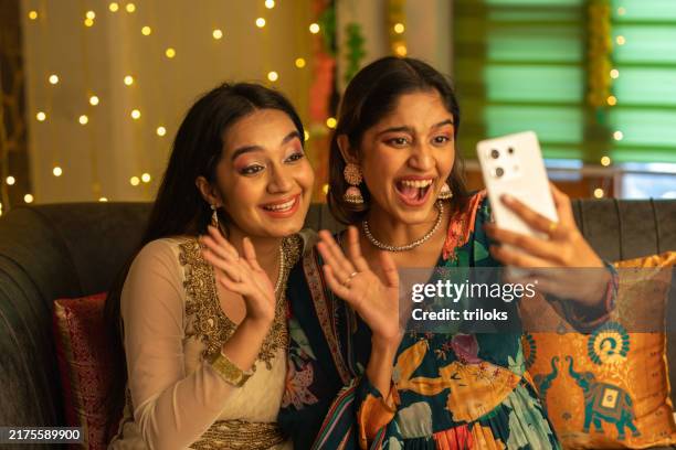 young sisters taking selfie over mobile phone at home during festival - family zoom stock pictures, royalty-free photos & images