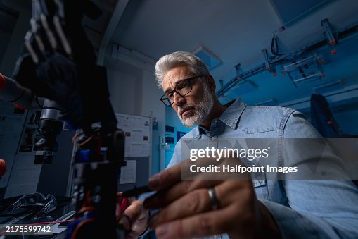 Robotics engineer adjusting, programming or calibring robotic prosthetic hand. Concept of modern technology in medicine. Robotic prosthetics, biomechatronics and neuroscience. Robotics engineer adjusting, programming or calibring robotic prosthetic hand. Concept of modern technology in medicine. Robotic prosthetics, biomechatronics and neuroscience.