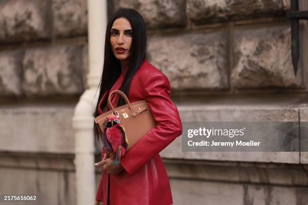 Farnoush Hamidian is seen wearing a buttoned red leather blazer, and a light brown leather “Birkin“ bag from Hermès with a multicolored parrot bag...