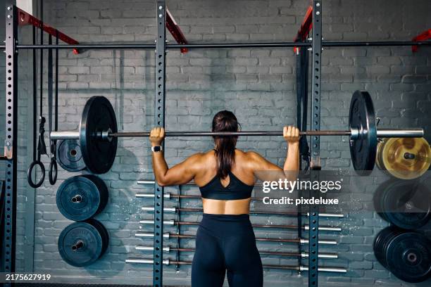 athlète féminine soulevant une barre lourde dans un environnement de gymnase. vue arrière d’une femme effectuant un exercice de musculation dans un studio de fitness. - poids-et-haltères photos et images de collection