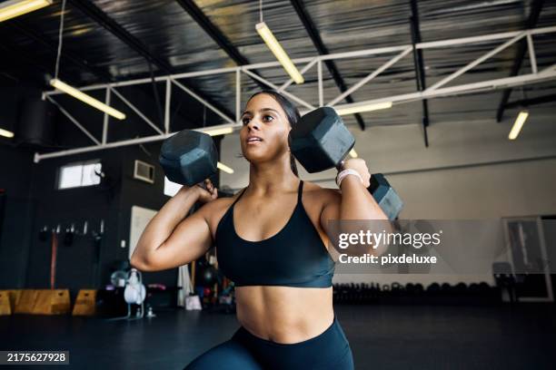atleta femenina fuerte que realiza estocadas con mancuernas en un gimnasio. vista frontal de una mujer sosteniendo pesas sobre los hombros durante el ejercicio de entrenamiento de fuerza en un gimnasio. - culturismo fotografías e imágenes de stock