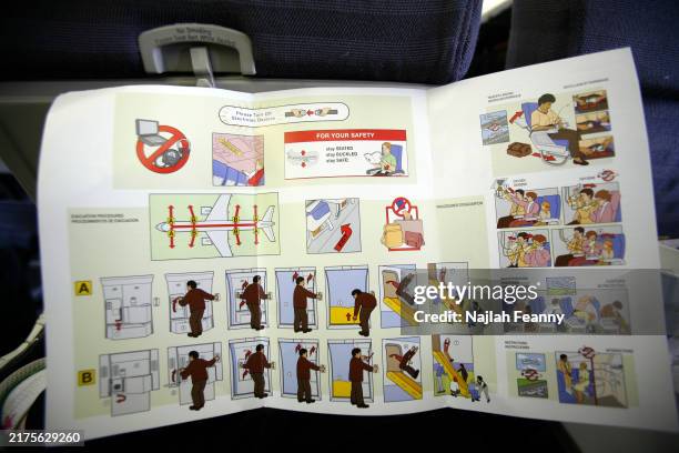 Michael Hicks and son Michael Hicks Jr. Look at the aircraft safety card while seated aboars a US Airways flight to Nassau. An aircraft safety card...