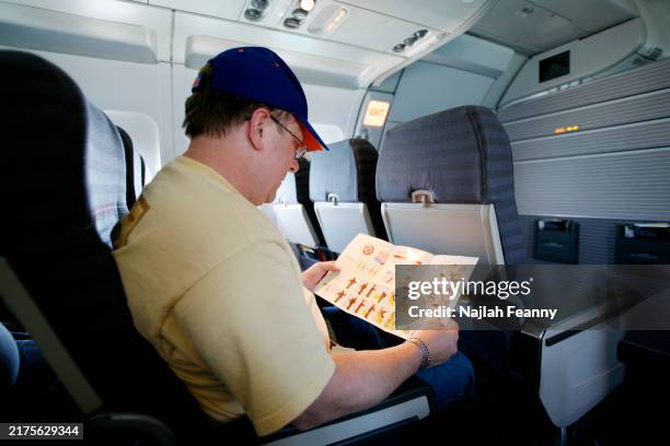 Michael Hicks and son Michael Hicks Jr. Look at the aircraft safety card while seated aboars a US Airways flight to Nassau. An aircraft safety card...