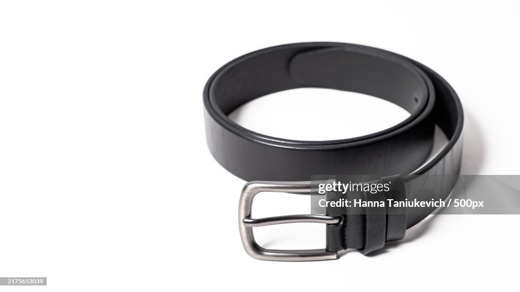 Twisted black leather belt with matted metal buckle isolated on white