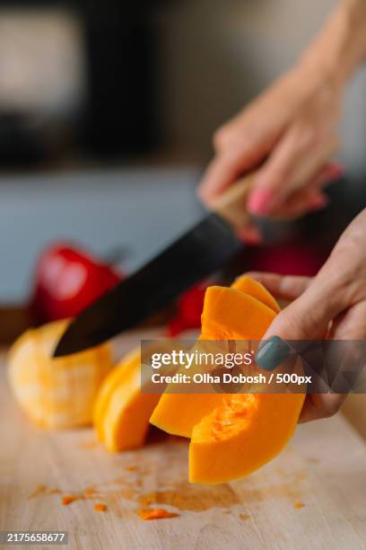 cropped hands cutting pumpkin on cutting board - affettare foto e immagini stock