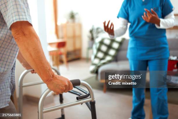 nicht wiederzuerkennende krankenschwester gibt einem älteren mann eine anleitung zur verwendung des gehers - ambulante behandlung stock-fotos und bilder