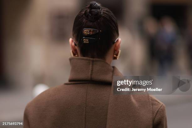 Anna Wein is seen wearing chunky squared earrings in gold; a brown wool trench coat paired with a wide long scarf, both from Sandro; and two...