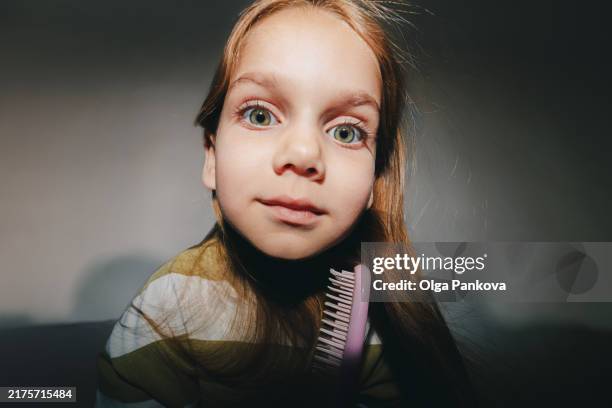 elementary girl combs her hair, looks at the camera and making faces - green eyes stock pictures, royalty-free photos & images