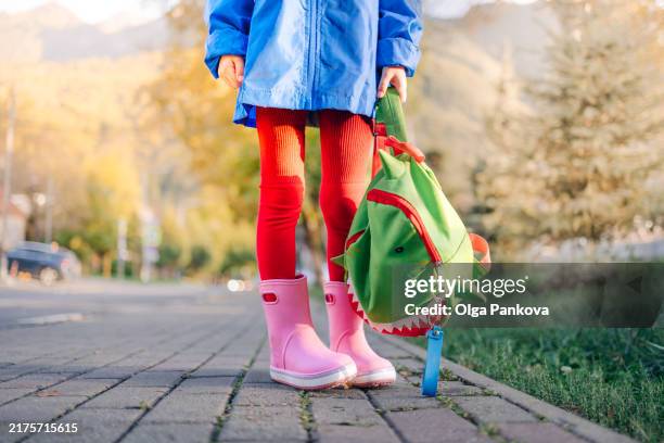 elementary girl walks down the street with a backpack in autumn - child backpack stock pictures, royalty-free photos & images