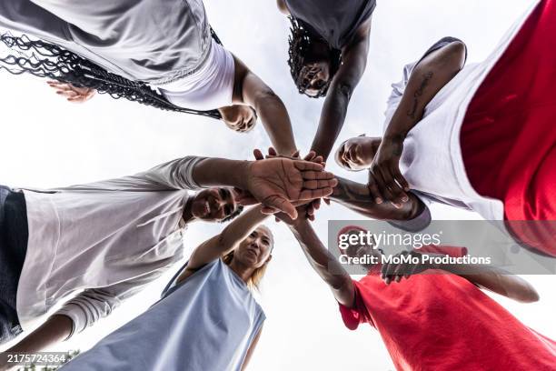 diverse group of female basketball players putting hands together in huddle on urban basketball court - medium group of people stock pictures, royalty-free photos & images
