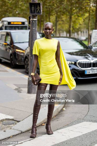 Adot Gak wears yellow asymmetric dress, brown over knees boots outside Stella McCartney during Womenswear Spring/Summer 2025 as part of Paris Fashion...