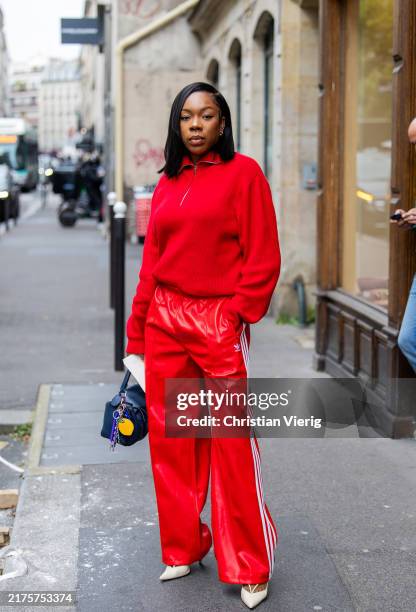 Guest wears red zipper, red leather pants, blue Loewe bag outside Sacai during Womenswear Spring/Summer 2025 as part of Paris Fashion Week on...