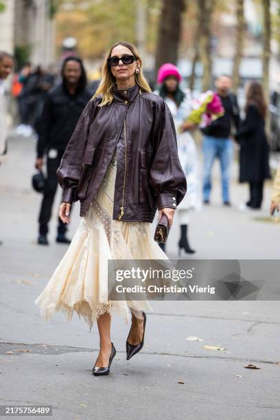 Candela Novembre wears brown leather jacket, beige pleated skirt, bag outside Zimmermann during Womenswear Spring/Summer 2025 as part of Paris...