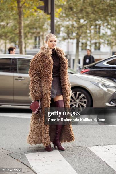 Leonie Hanne wears long over knee burgundy leather boots, burgundy mini skirt, burgundy top, brown fur coat and burgundy bag and sunglasses outside...