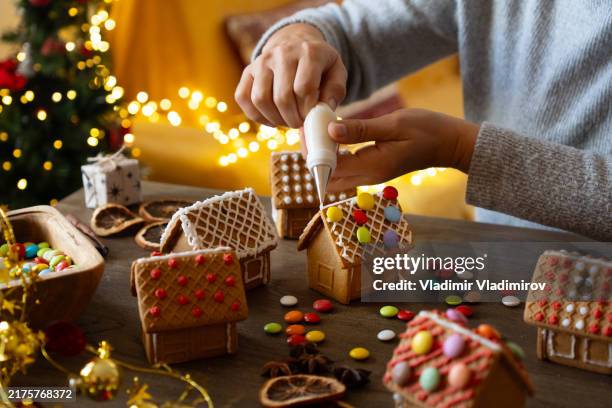 decorating gingerbread houses for family holidays - eating peppermint candy stock pictures, royalty-free photos & images