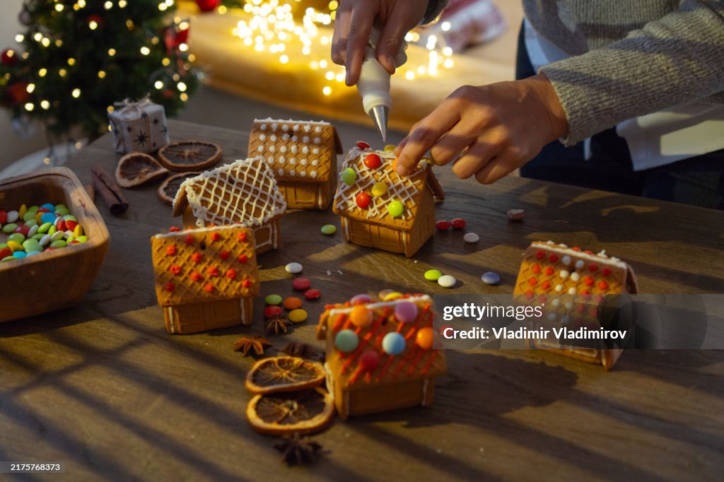 Decorating gingerbread houses on the table in a cozy christmas atmosphere