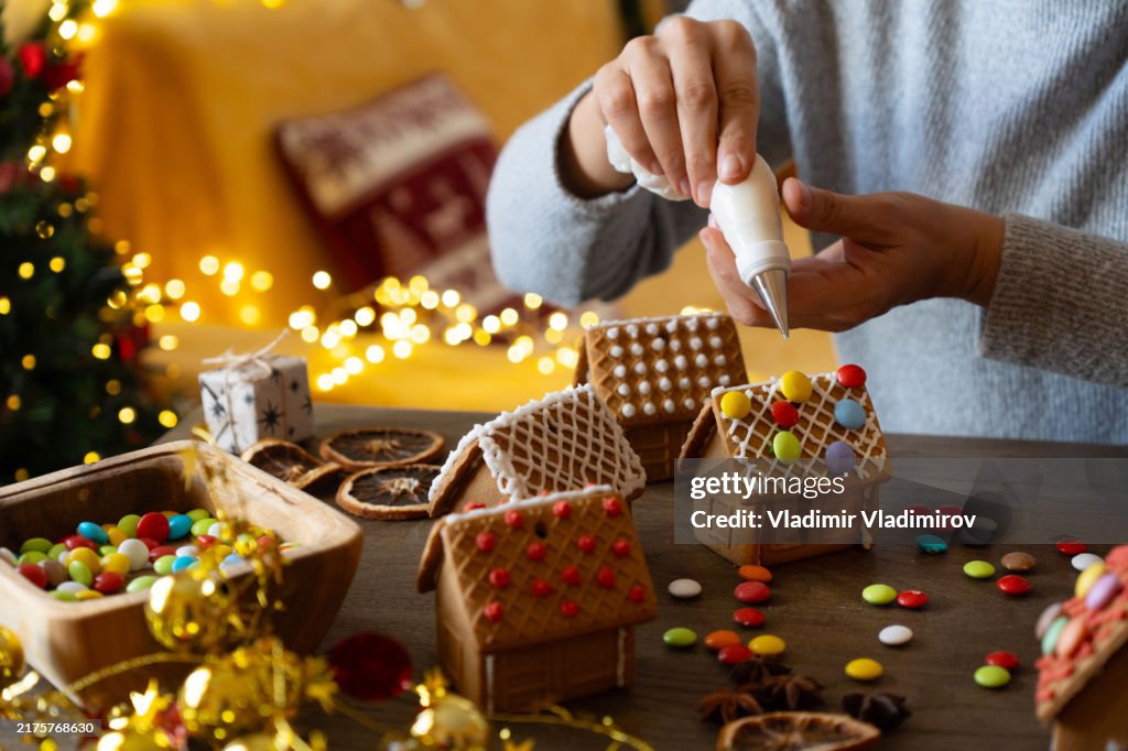 A woman is decoration ginger bread houses for Christmas