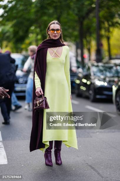 Guest wears rimmed sunglasses with orange lenses, dark red maroon large scarf, light green long sleeve midi dress, shiny dark red maroon crocodile...