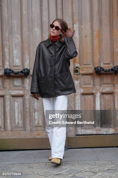Guest wears dark brown sunglasses, bright red turtle neck long sleeve shirt, shiny black oversized jacket, dark brown leather gloves, white pants,...