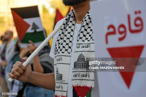 People wave flags and wear the Palestinian keffiyeh as they take part in a protest in solidarity with Gaza and Lebanon in the Bahraini capital Manama...