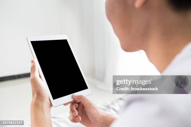 glücklicher mann, der sein tablet in seinem schlafzimmer benutzt - mock email stock-fotos und bilder