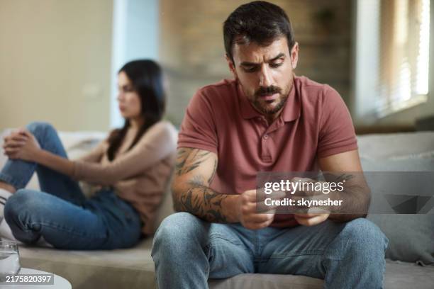 young man feeling displeased after a conflict with his girlfriend at home. - menselijke relaties stockfoto's en -beelden