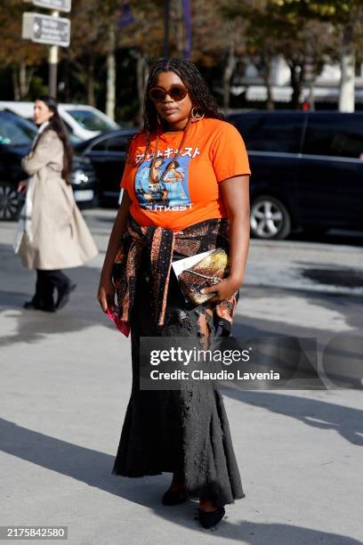 Gabriella Karefa Johnson wears orange printed t-shirt, black distressed maxi skirt, brown decorated Chanel bag, outside Chanel, during Womenswear...