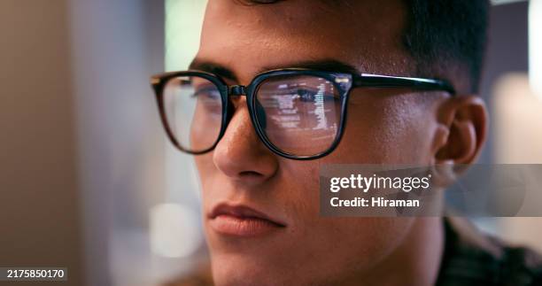 focused young programmer in low light setting wearing glasses reflecting code on screen - staring at screen stock pictures, royalty-free photos & images