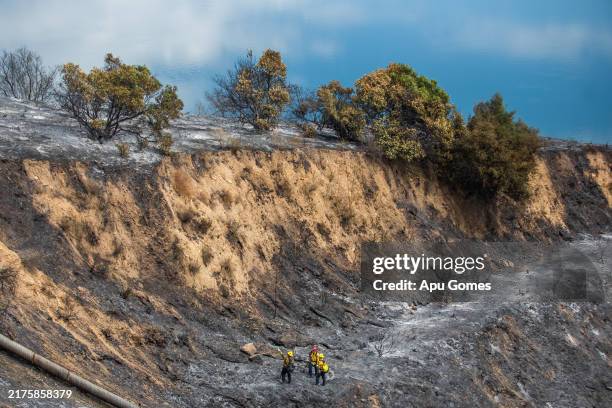 Firefighters work to control hotspots next to Lake Piru at Los Padres National Forest, where the Felicia Fire has burned more than 300-acres on...