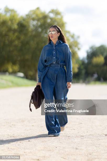 Tamara Kalinic wears white pumps, a burgundy leather bag, gold sunglasses, silver earrings and a denim jumpsuit outside Loewe show during Womenswear...