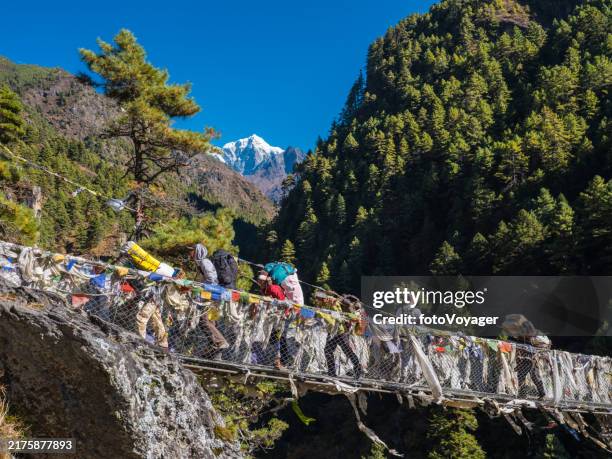 nepal sherpa porters hikers crossing canyon wire bridge himalayan mountains - namche bazaar stock pictures, royalty-free photos & images