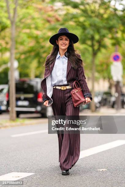 Guest wears black hat, white buttoned up long sleeve shirt, dark red maroon white lined blazer jacket, beige gold buckle leather belt, dark red white...