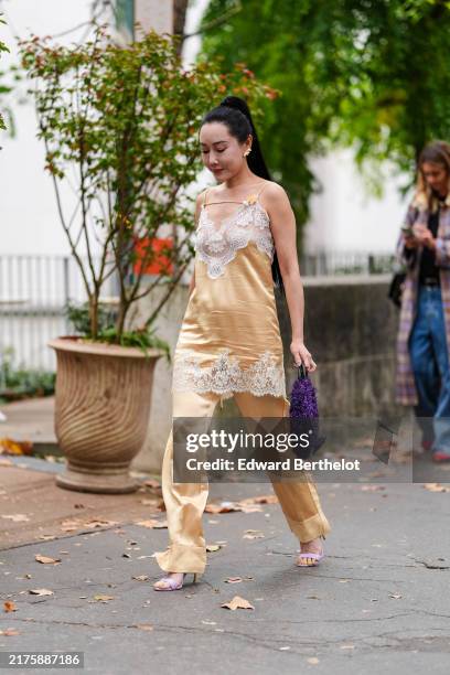 Guest wears gold earrings, shiny dark yellow satin white sheer mesh lace top, shiny dark yellow satin loose pants, light purple open toe heeled...