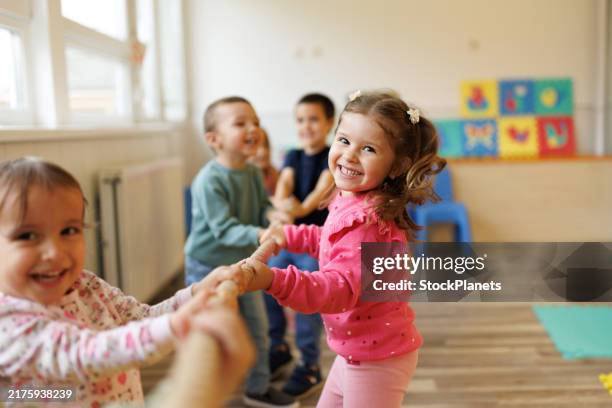 niños felices jugando un juego de tira y afloja en la sala de juegos - niñez fotografías e imágenes de stock
