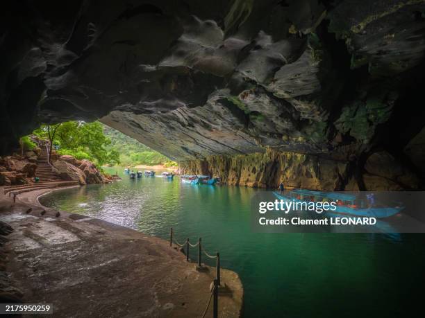 view of the entrance of the phong nha cave, with its underground river, its turquoise colored waters, small touristic rowing boats and the quays, phong nha-ke bang national park (phong nha-kẻ bàng) - quang binh province - north vietnam. - limestone stock pictures, royalty-free photos & images