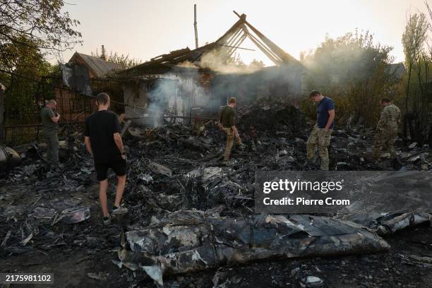 Ukrainian servicemen examine the wreckage of a downed Russian aircraft, likely a Sukhoi S-70 "stealth" heavy unmanned combat aerial vehicle , which...