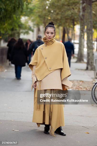 Guest wears pale yellow long skirt with tassels, off white and yellow checkered jacket and pale yellow cape on top during Womenswear Spring/Summer...