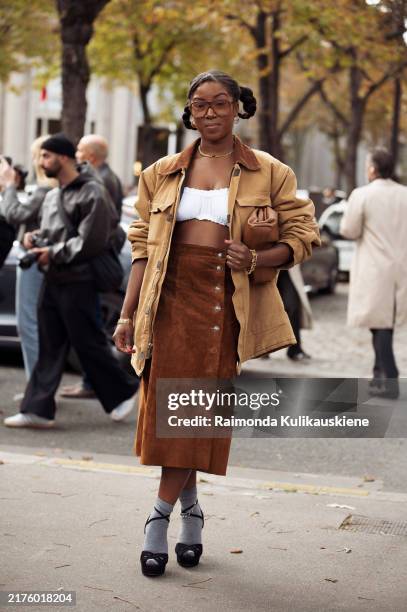 Guest wears brown long skirt, white crop top, brown jacket, grey socks and high heels and brown bag outside the Miu Miu show during Womenswear...