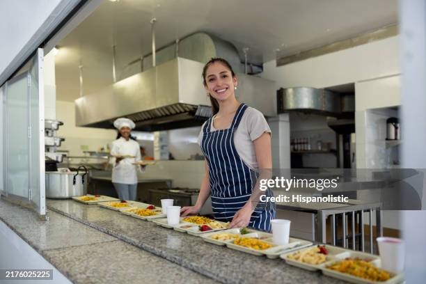 happy waitress working at a school cafeteria and smiling - elementary school cafeteria stock pictures, royalty-free photos & images