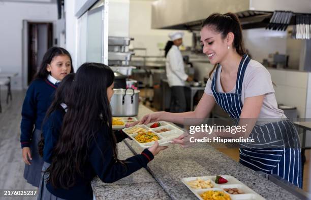 happy waitress serving the school lunch to elementary students - merenda escolar imagens e fotografias de stock