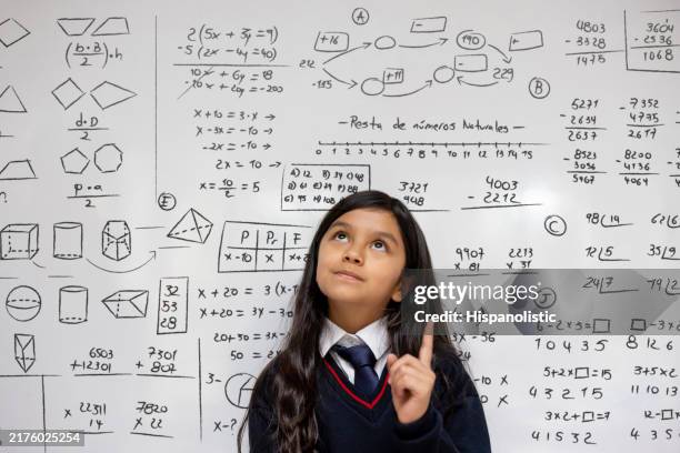 schoolgirl in a math class thinking about a problem and leaning against the whiteboard - simbolos-matematicos imagens e fotografias de stock
