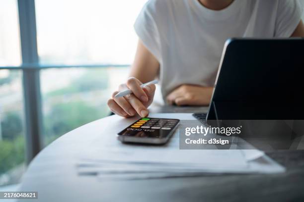 asian woman managing personal banking and finance. paying bills online. making financial plans. planning budget and calculating expenses with digital tablet while going through bills at home. home finances. home budgeting. banking and finance concept - studiengebühren stock-fotos und bilder
