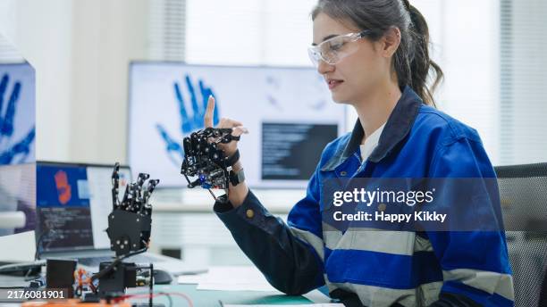 woman engineer developer in robotics arm prototype demonstrating a practical robotics in human-machine interaction controller and checking robotic parts hardware and applied software - mechatronics stockfoto's en -beelden