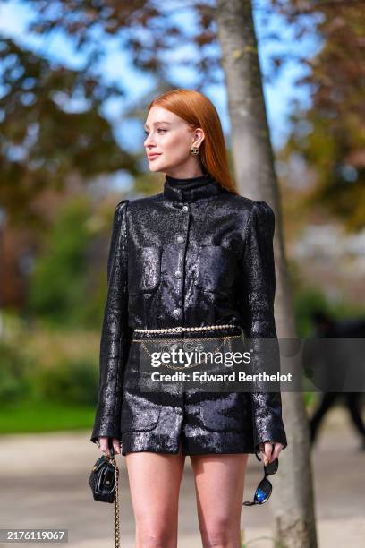 Marina Ruy Barbosa wears shiny black Chanel leather blazer jacket, gold chain belt, white beaded belt, shiny black quilted Chanel leather mini bag,...