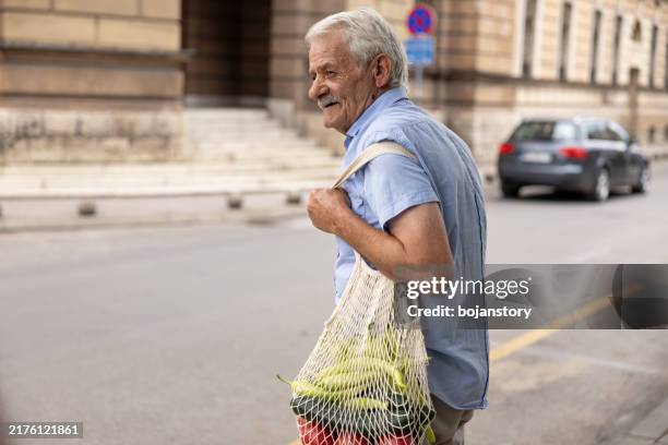 senior man returning home from grocery shopping - reusable bag stock pictures, royalty-free photos & images
