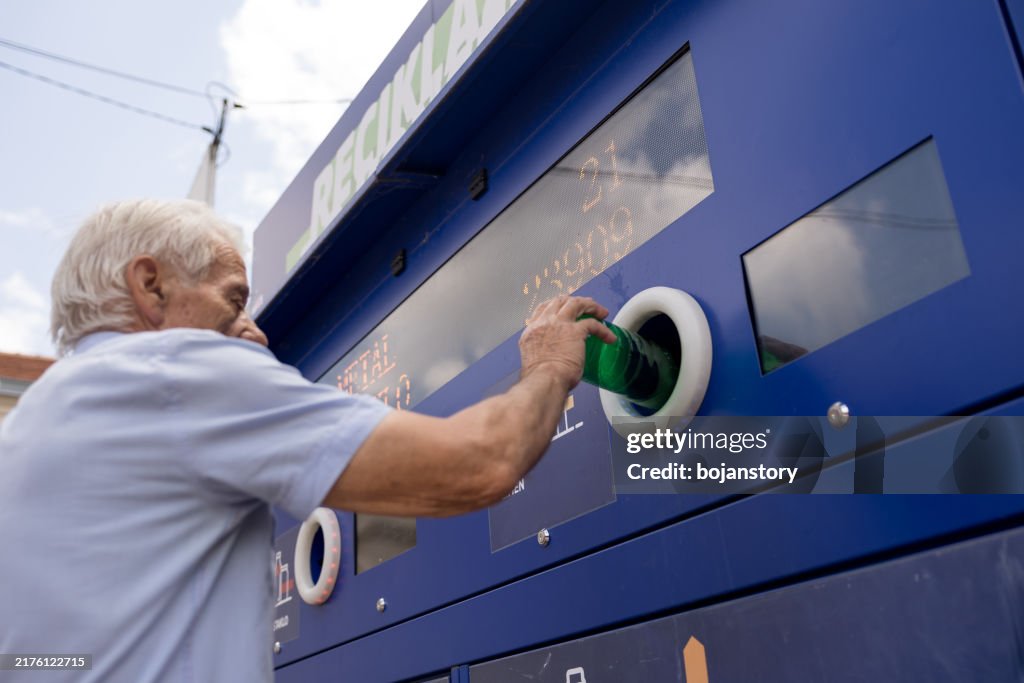 Senior man recycling plastic bottles in a machine