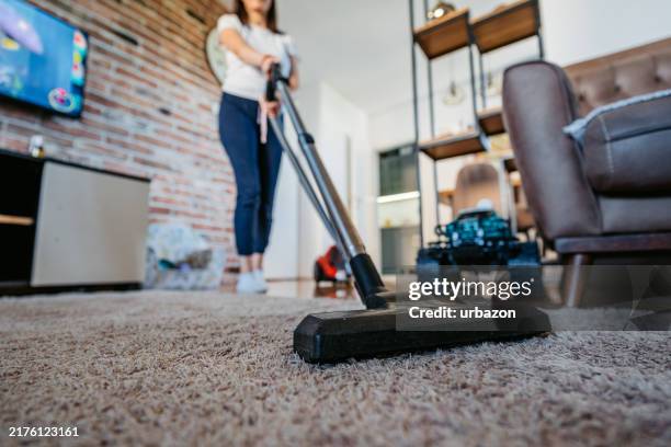 mid-adult woman vacuuming her apartment - maid lounging stock pictures, royalty-free photos & images