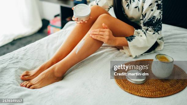 woman at home using shea butter body cream - shea butter stock pictures, royalty-free photos & images